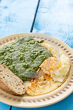 Boiled spinach with fried egg and a slice of bread