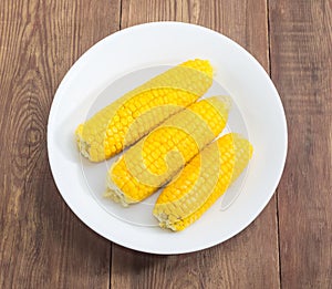 Boiled sweet corn on white dish on the rustic table