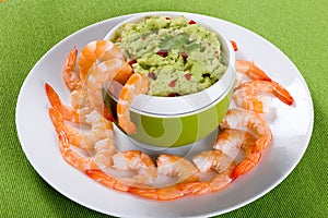 Boiled tiger prawns tails on plate with guacamole sauce