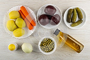 Boiled vegetables, canned green peas, gherkins, onion, salt, vegetable oil for cooking vinaigrette on table. Top view