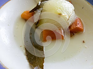 boiled vegetables on a plate of broth .