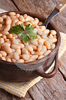 Boiled white kidney beans in a brown pot closeup vertical