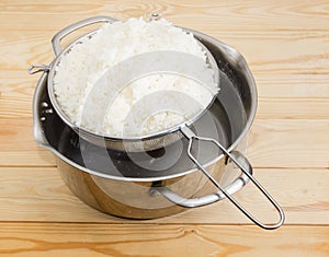 Boiled white rice in stainless steel sieve over stock pot