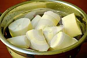 Boiled yucca in metal container.