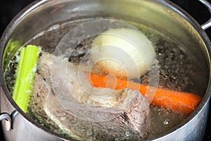 Boiling beef broth in steel stewpan close up