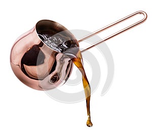Boiling coffee drink pouring from copper coffee cezve on white background. File contains clipping path