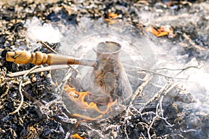 Boiling coffee in turkish cezva on campfire coals