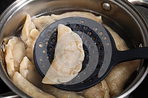 Boiling delicious dumplings (varenyky) on skimmer over pot, closeup