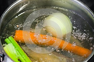 Boiling meat broth in steel stewpan close up