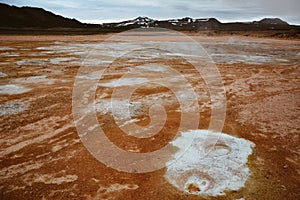 Boiling mudpots in the geothermal area Hverir and cracked ground around, Iceland in summer. Myvatn region, North part of Iceland