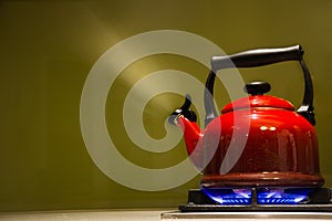 Boiling red kettle on blue gas flames