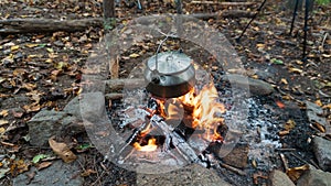 Boiling tea with a pot over a Bushcraft campfire. Primitive survival lean to shelter in the Blue Ridge Mountains of Asheville, Nor