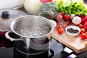 Boiling water in a cooking pot on the cooker photo