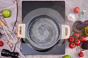 Boiling water in a cooking pot an a pan on a induction stove at domestic kitchen