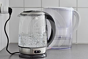 Boiling water in a glass kettle and water in a mug from