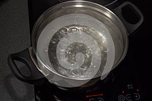 Boiling water in pan on electric stove in the kitchen