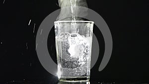 Boiling water is poured into a glass. Steam and bubbles are clearly visible in the backlight.