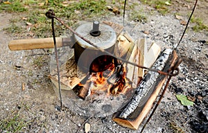 Boiling water on red hot coals in forest. Make campfire cooking. Bonfire to heat water or food while camping in nature. Camping in