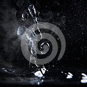 Boiling water splash with steam on black background closeup