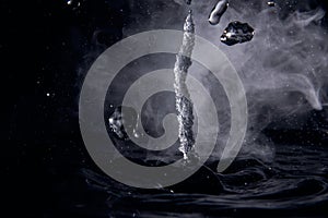 Boiling water splash with steam on black background closeup