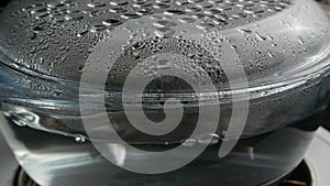 Boiling water in transparent glass saucepan with condensation