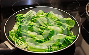Bok choy stir fry on pan. Stir fried vegetables in a chinese wok. Stalks of baby bok choy cooking on the pan