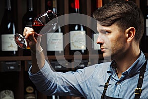 Bokal of red wine on background, male sommelier appreciating drink