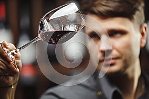 Bokal of red wine on background, male sommelier appreciating drink