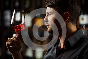 Bokal of red wine on background, male sommelier appreciating drink