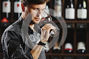 Bokal of red wine on background, male sommelier appreciating drink