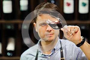 Bokal of red wine on background, male sommelier appreciating drink