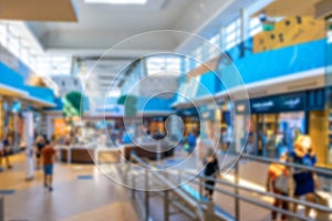 Bokeh Shopping mall background. Interior of retail centre store in soft focus. People shopping in modern commercial mall center.