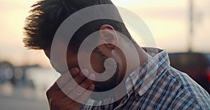 Bokeh shot of depressed young man standing outdoors on city street