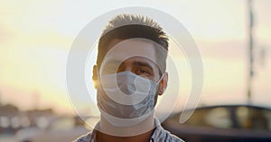 Bokeh shot of young man wearing protective mask on at city street in evening