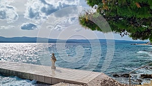 Bol - White stone sculpture of girl with lifebelt on a pier in coastal town of Bol island Brac, Dalmatia, Croatia