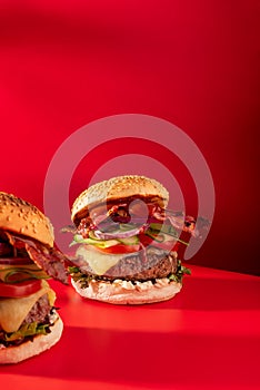 Bold fresh cheeseburger loaded with lettuce, cucumber, tomato and bacon on vibrant red