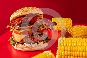 Bold fresh cheeseburger loaded with lettuce, cucumber, tomato and bacon on vibrant red