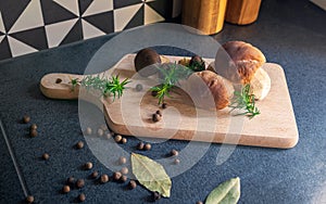 Boletes and bay boletes placed on a cutting board surrounded by spices,