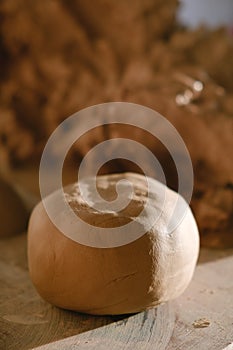 Boll of clay lying on wooden table prepared for pottery wheel