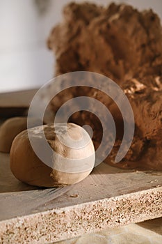 Boll of clay lying on wooden table prepared for pottery wheel