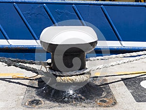 Bollard at a harbor pier with ship.