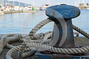 Bollard from iron with a ship rope at the pier on the port