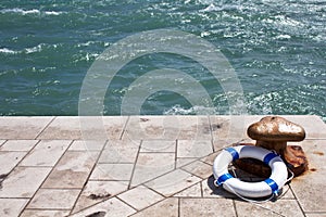 Bollard and lifebuoy, lifebelt on a pier by the sea