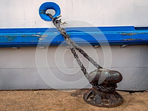 Bollard on a pier or quay, with mooring line from boat laid on it