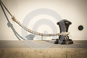 Bollard on a pier or quay, with mooring line from boat laided on it.