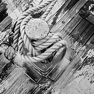 Bollard with a rope on the wooden deck of a sailing vessel