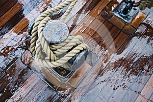 Bollard with a rope on the wooden deck of a sailing vessel, close-up