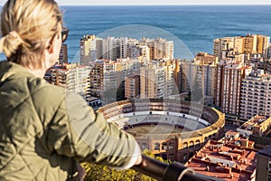 Bolnde female touris enjoying amazing panoramic aerial view of bull ring in Malaga, Spain photo