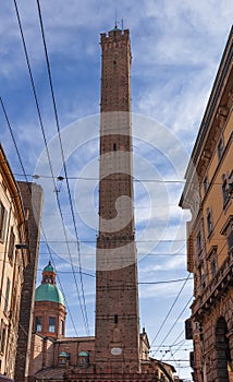 Vertical view of Bologna Asinelli Tower piercing sky, surrounded by tram wires photo