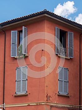 Bologna house window decorated with flowers and wooden shutters